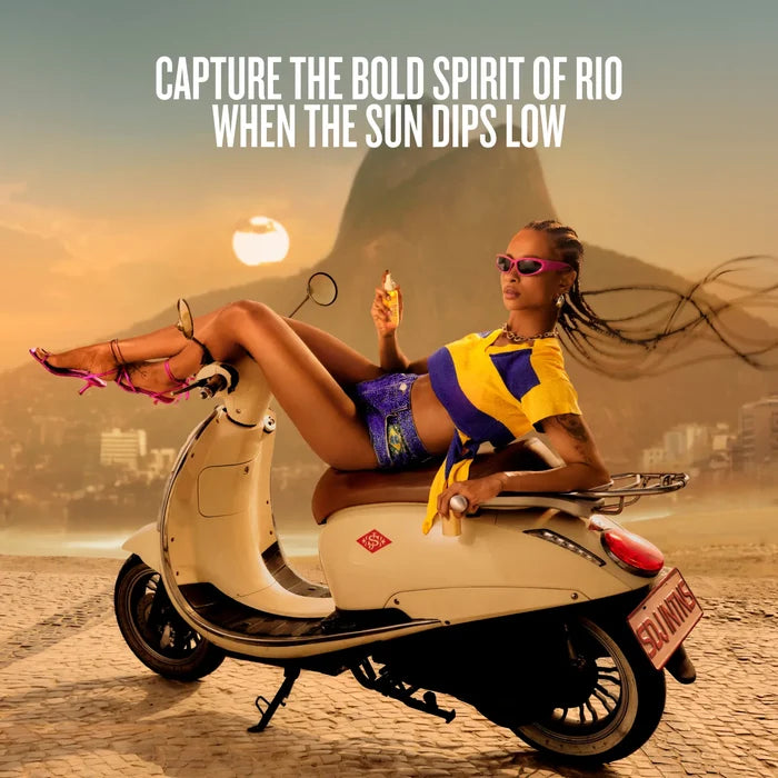 A woman reclining on a cream-colored scooter on a beach with a warm sunset sky, large text at the top reading 'CAPTURE THE BOLD SPIRIT OF RIO WHEN THE SUN DIPS LOW', and a Rio de Janeiro mountain backdrop.