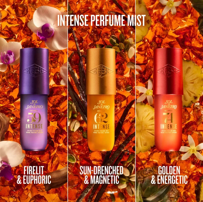 Three perfume mist bottles from SOL JANHEIRO are displayed side-by-side against a rich background of orange flower petals, vanilla beans, and white orchids. The bottles feature metallic purple, gold, and red finishes with gold lettering, labeled 'INTENSE PERFUME MIST' at the top and three scent names at the bottom: 'FIRELIT & EUPHORIC', 'SUN-DRENCHED & MAGNETIC', and 'GOLDEN & ENERGETIC'.