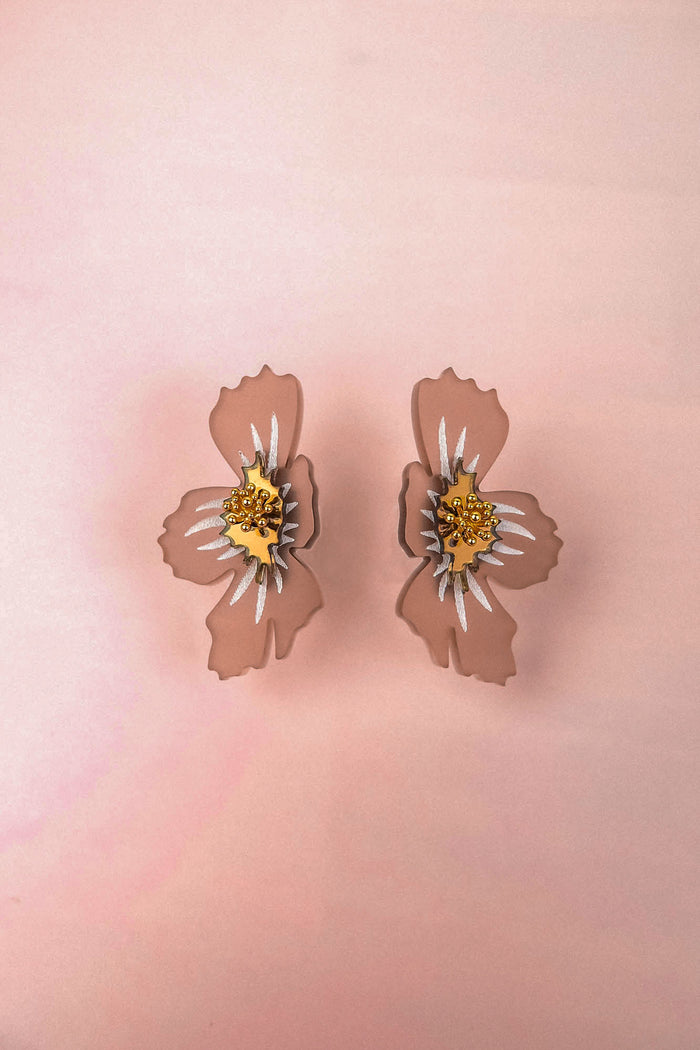A pair of light pink acrylic flower earrings with yellow and white centers, displayed on a soft pink background. These handmade earrings feature a delicate frosted finish that adds an elegant touch to any outfit.