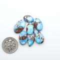 Golden Hills Turquoise cabochons, icy blue to lavender tones with chocolate matrix, polished stones on a white background with a US dime for scale