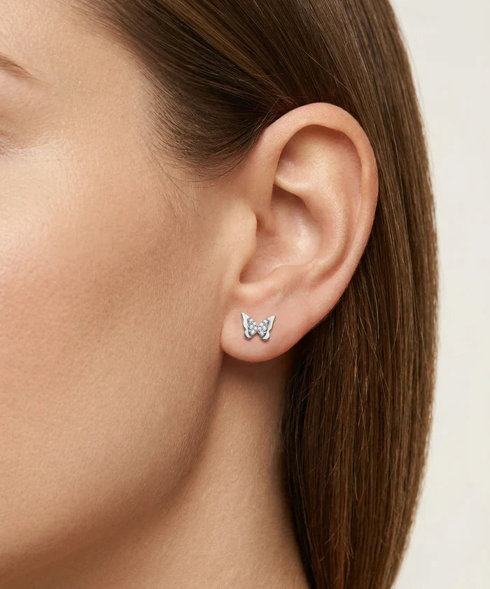 Butterfly-shaped earrings worn by a person with brown hair.
