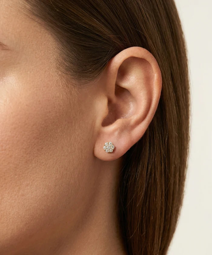 Close-up of an ear wearing a floral earring with a plain background