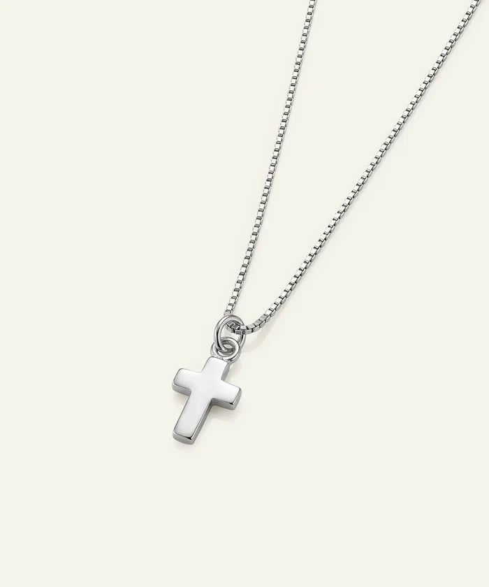 A silver cross pendant necklace on a delicate silver ball chain, displayed against a solid off-white background.