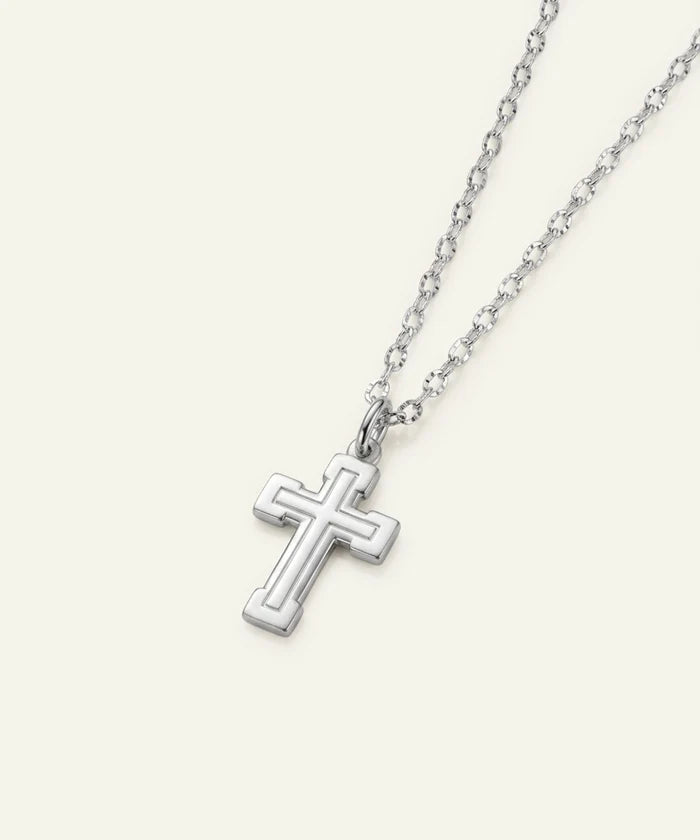 A silver cross pendant necklace with a matching chain, shown on a light cream background.