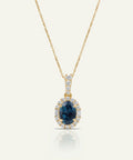 Gold necklace with a blue gemstone pendant on a white background