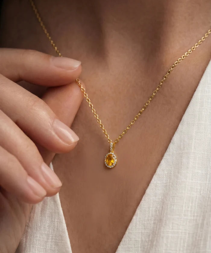 Gold necklace with a yellow gemstone worn by a person