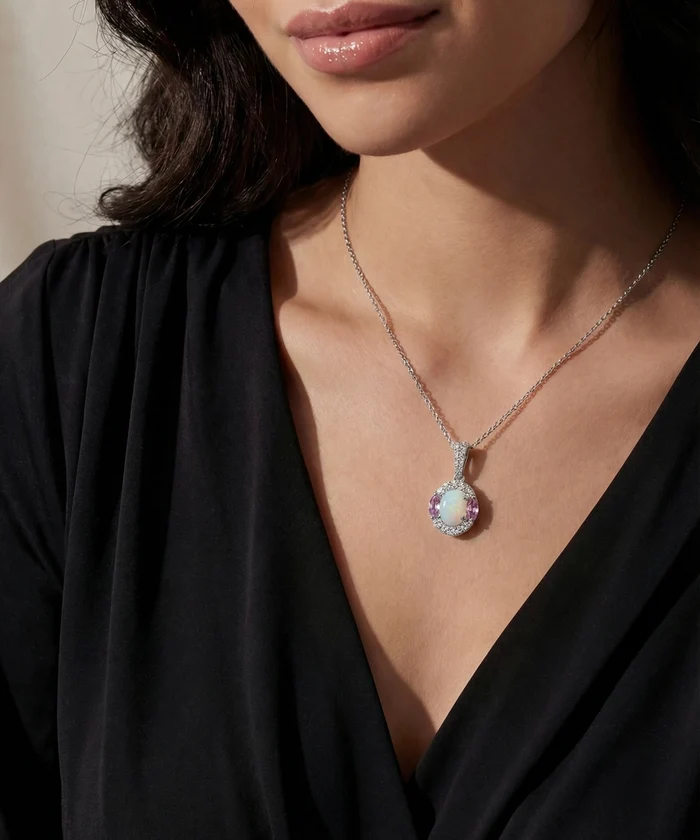 Close-up of a woman wearing a black top with a necklace featuring an opal pendant.