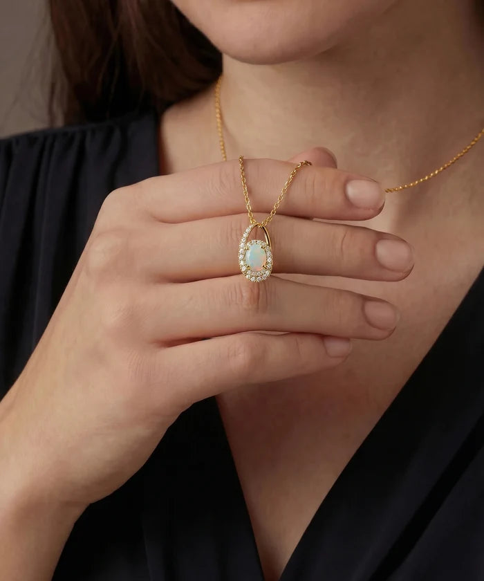 Gold necklace with a pendant held by a hand against a neutral background