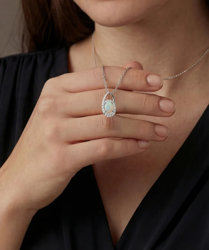 Close-up of a person wearing a silver necklace with an emerald pendant.