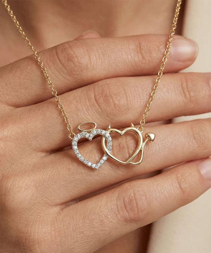 Gold necklace with interlocking heart pendants held by a hand