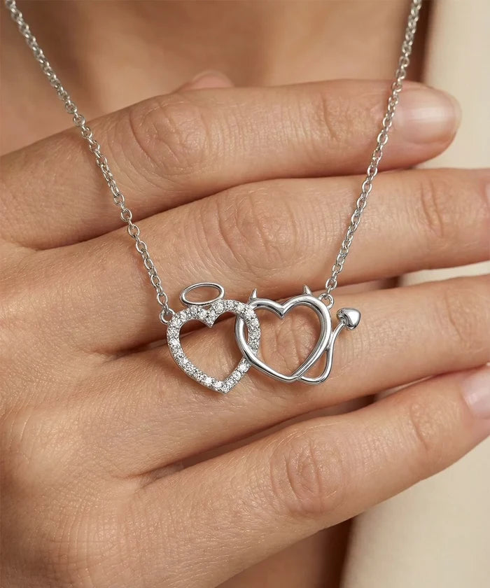 Silver necklace with interlocking heart pendants held by a hand