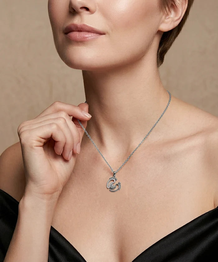 Woman wearing a silver necklace with a heart pendant against a neutral background