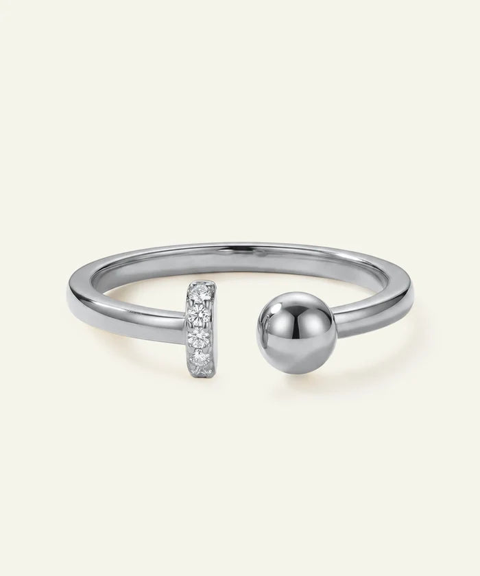 Silver ring with a spherical design and small diamond accents on a light gray background