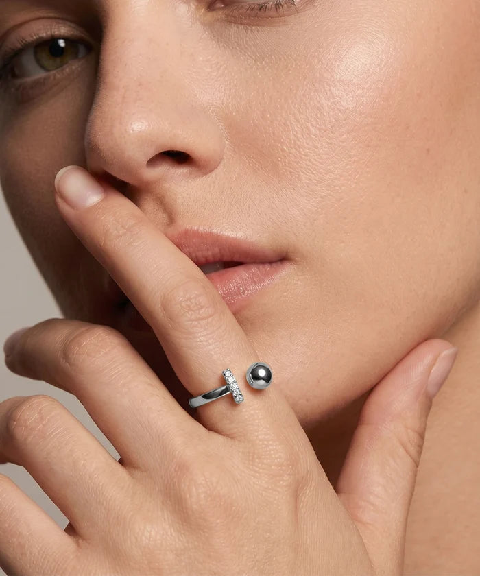 Close-up of a woman's hand wearing a silver ring with a black pearl and small diamonds.