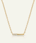 Gold necklace with a bar pendant on a light beige background