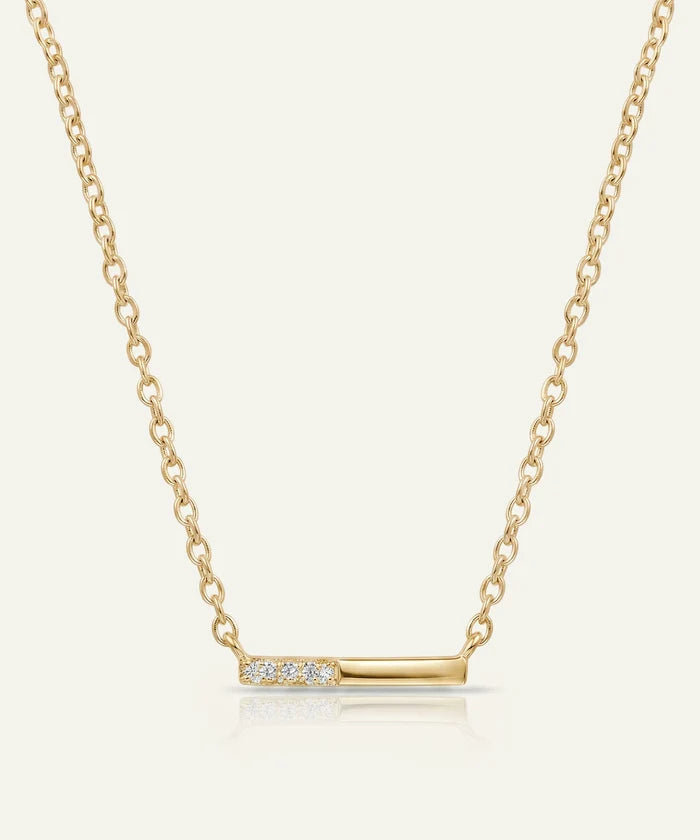 Gold necklace with a bar pendant on a light beige background