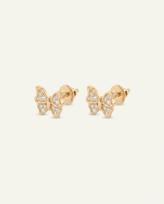 A pair of gold butterfly stud earrings paved with small round clear diamonds, displayed side by side against a light off-white background.