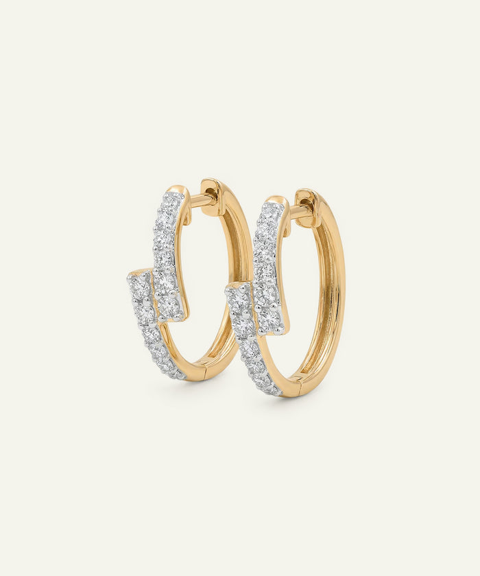 Gold hoop earrings with diamond accents on a light gray background