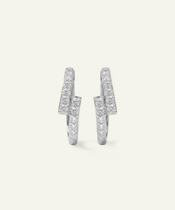 Pair of silver hoop earrings with clear gemstones on a light gray background