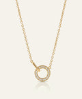 Gold necklace with a circular pendant on a light beige background