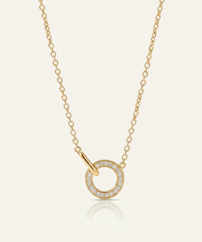 Gold necklace with a circular pendant on a light beige background