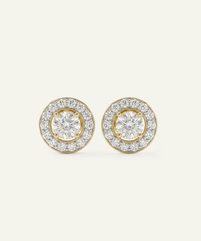 Pair of gold and diamond earrings on a light beige background
