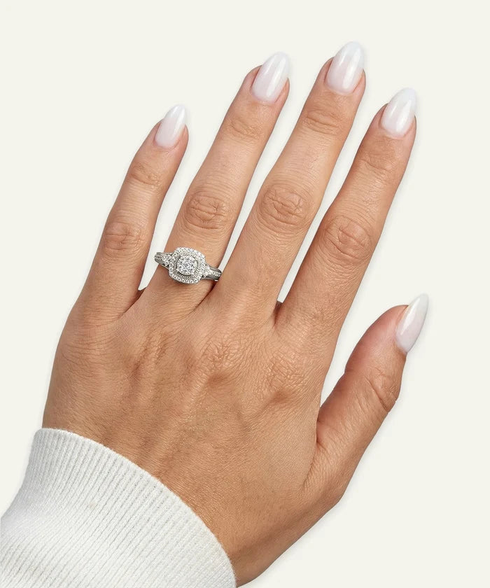 Hand wearing a diamond ring with a plain background