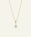 Gold necklace with a small diamond pendant on a light gray background