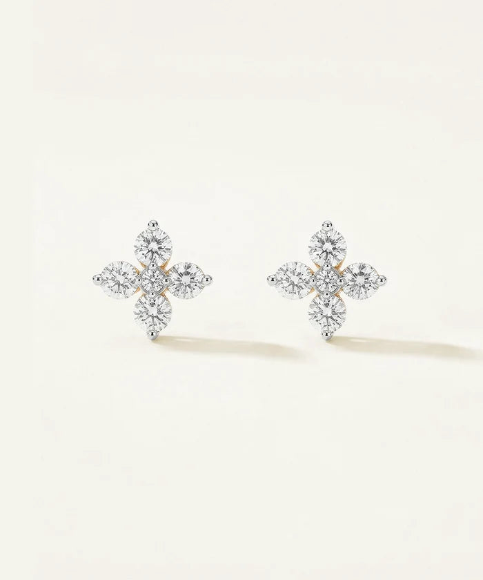 Pair of diamond-cross earrings on a light beige background