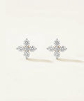 Pair of diamond-cross earrings on a light beige background