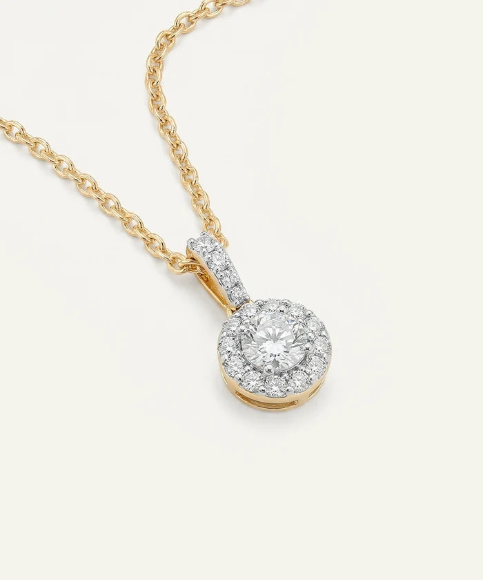 Gold necklace with a diamond pendant on a light gray background