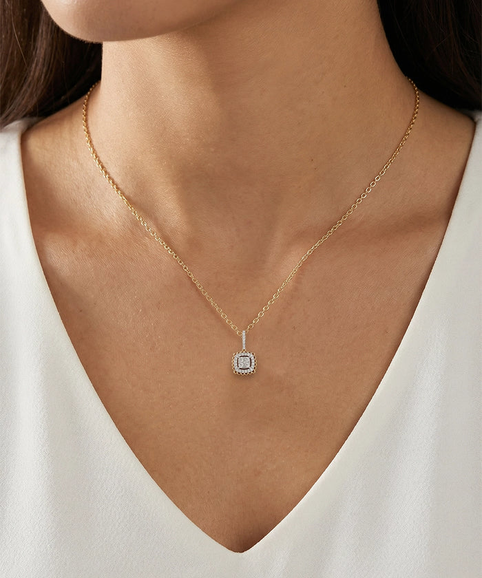 Gold necklace with a pendant worn by a person in a white top
