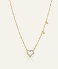 Gold necklace with a heart-shaped pendant on a light beige background