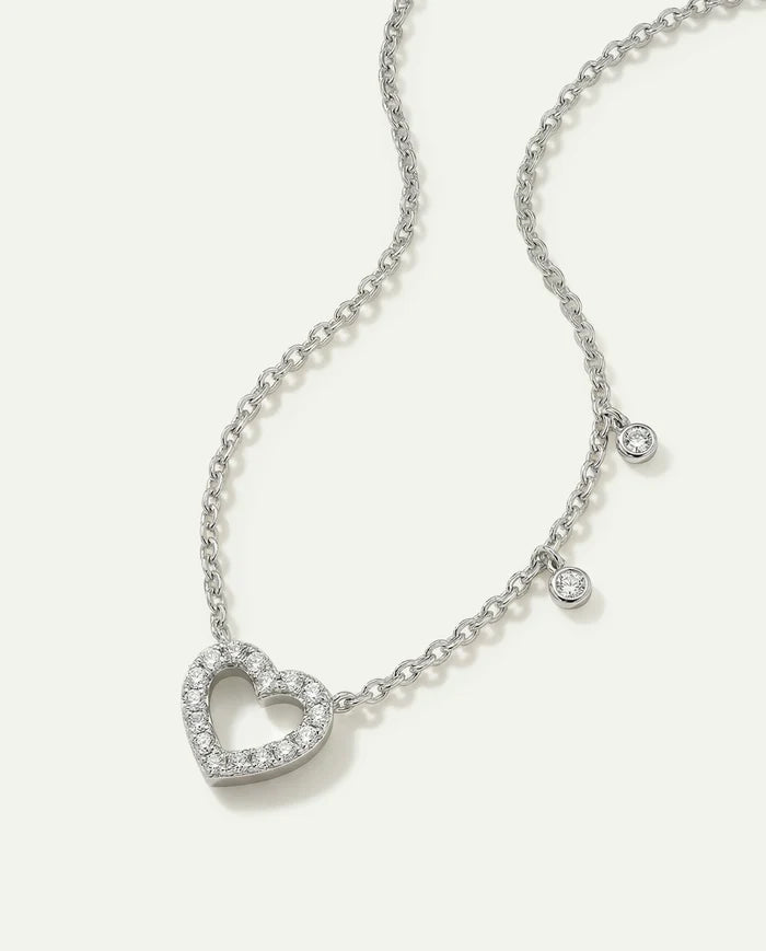 Silver necklace with a heart-shaped pendant on a light gray background