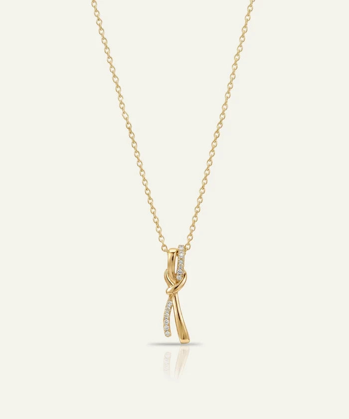 Gold necklace with a delicate pendant on a light beige background
