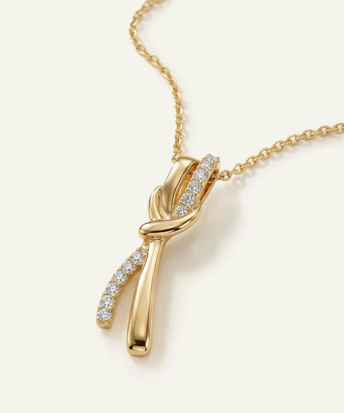 Gold necklace with a diamond pendant on a light beige background