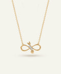 Gold infinity necklace with arrow pendant on a light beige background
