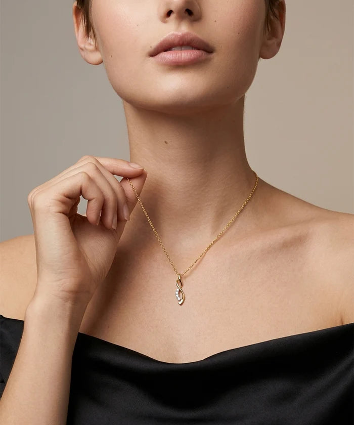 Woman wearing a silver necklace with a black top against a neutral background