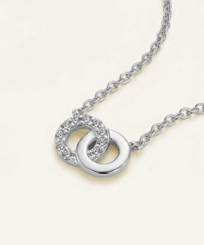 Silver necklace with interlocking rings on a light beige background