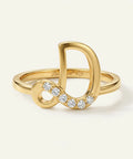Gold ring with infinity symbol and diamonds on a light beige background
