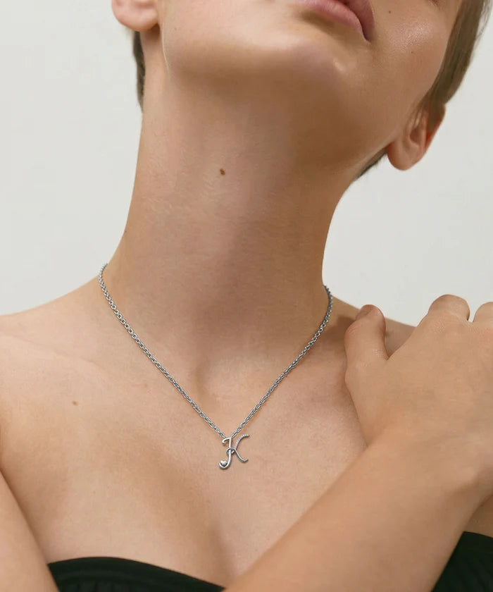 Gold necklace with a letter 'J' pendant on a neutral background