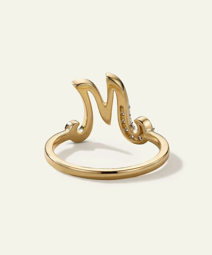 Gold ring with letter 'M' design on a white background