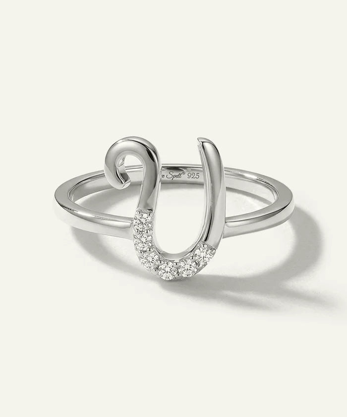 Silver ring with a horseshoe design and embedded stones on a white background