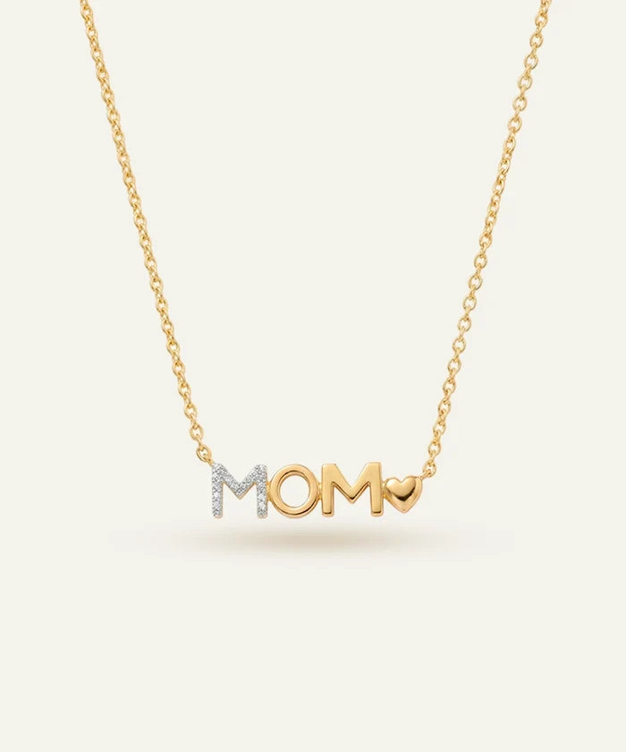 Gold necklace with 'MOM' pendant on a light beige background