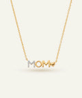 Gold necklace with 'MOM' pendant on a light beige background