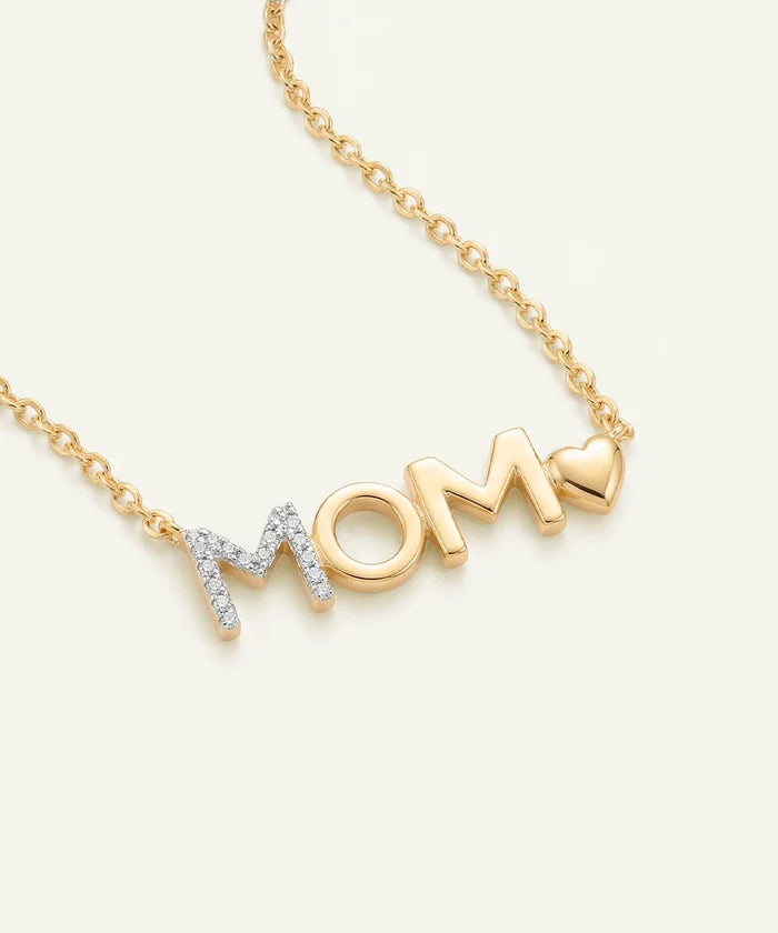 Gold necklace with 'MOM' pendant on a light beige background