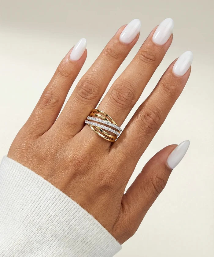 Hand wearing a gold ring with a diamond band on a neutral background