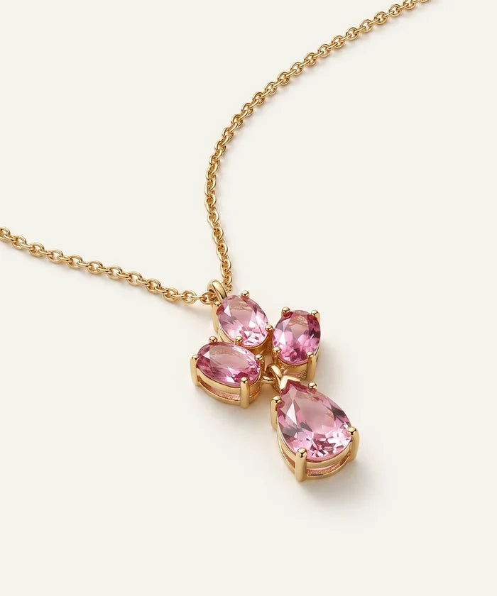 A gold chain necklace featuring a pendant with three pink gemstones in a floral cluster setting, displayed on a light cream background.