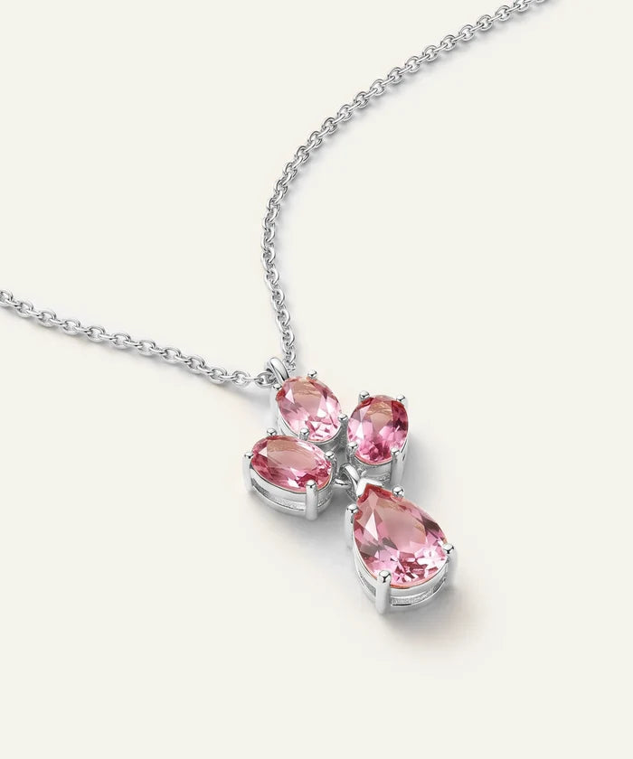 A silver-tone necklace featuring a multi-stone pendant with four pink gemstones in pear and oval cuts, set on a delicate chain against a light cream background.