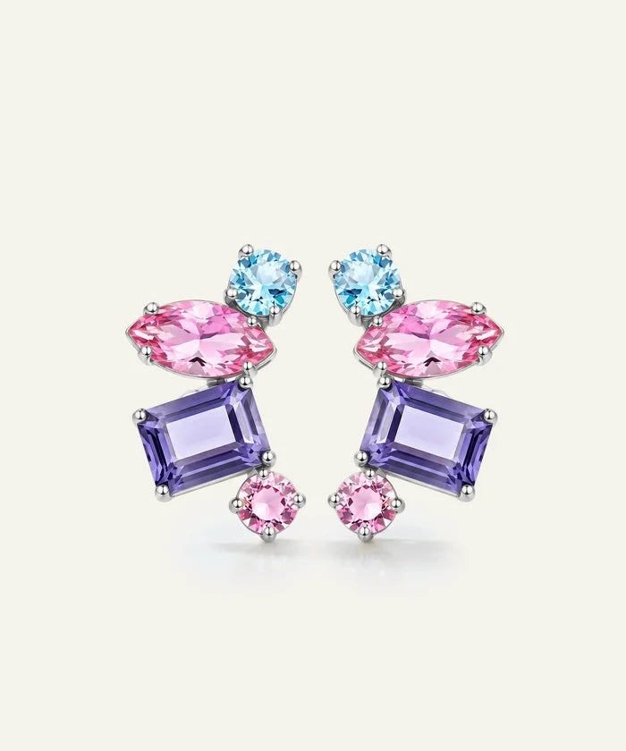 A pair of colorful gemstone stud earrings featuring light blue round crystals, pink marquise-shaped crystals, and lavender rectangular crystals set in silver-toned metal, displayed on a light cream background.